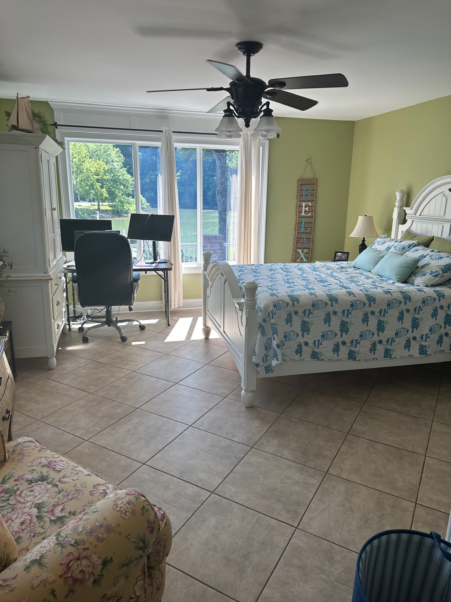 Green bedroom with desk, white bed and sliding glass doors to the lake