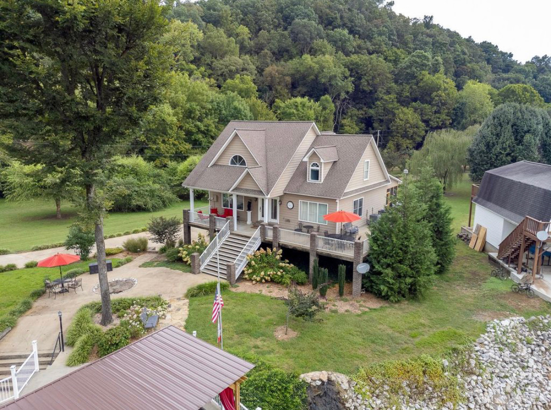 Aerial view of House #1, decks, fire pit and wooded hillside