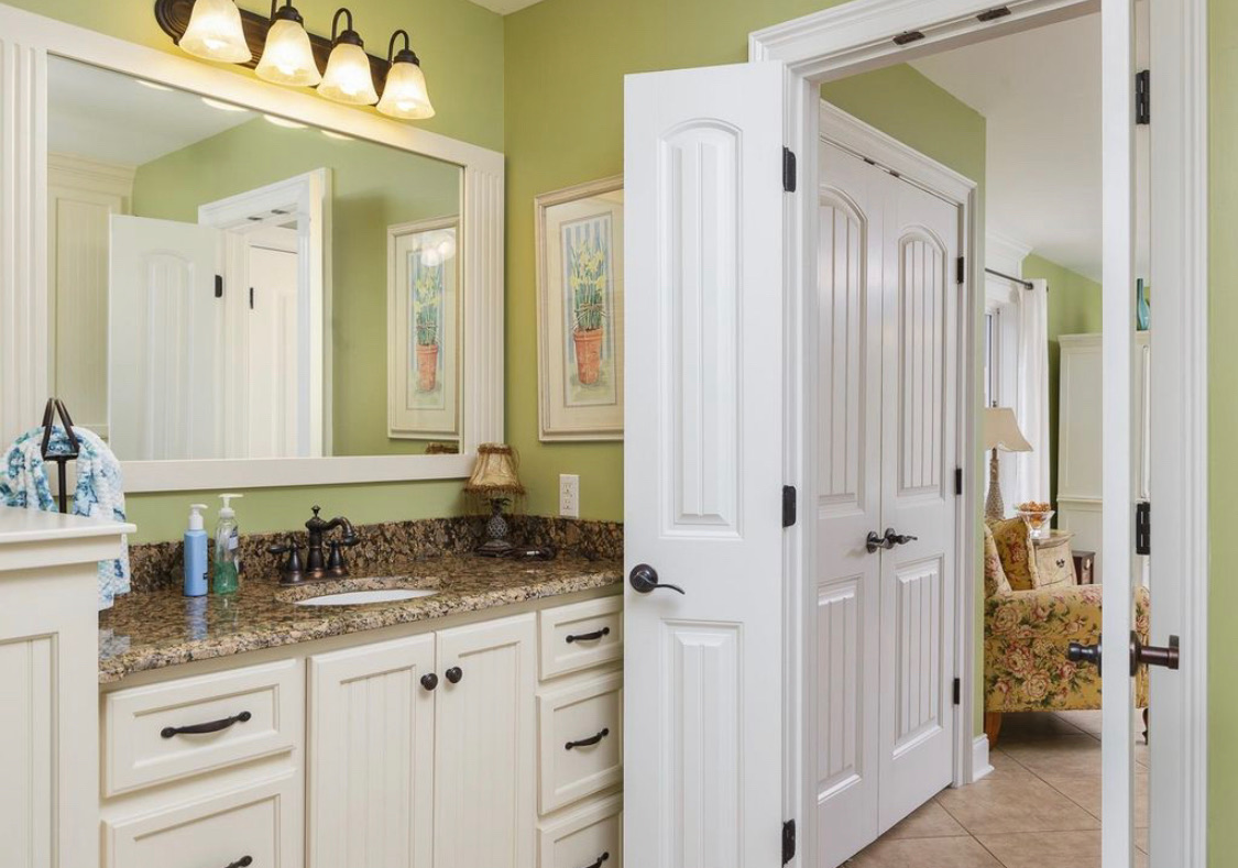 Green bathroom with white vanity, granite counters and garden art