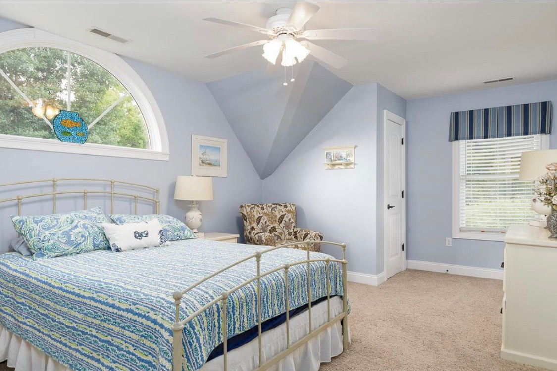 Blue bedroom with arched window, sitting chair and coastal decor