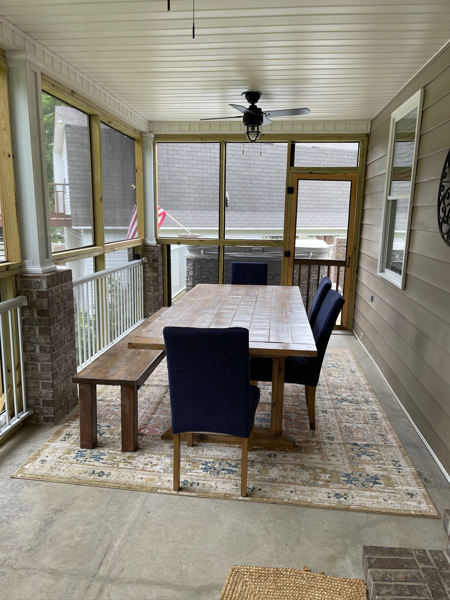 Screened porch with farmhouse dining table, bench and navy chairs
