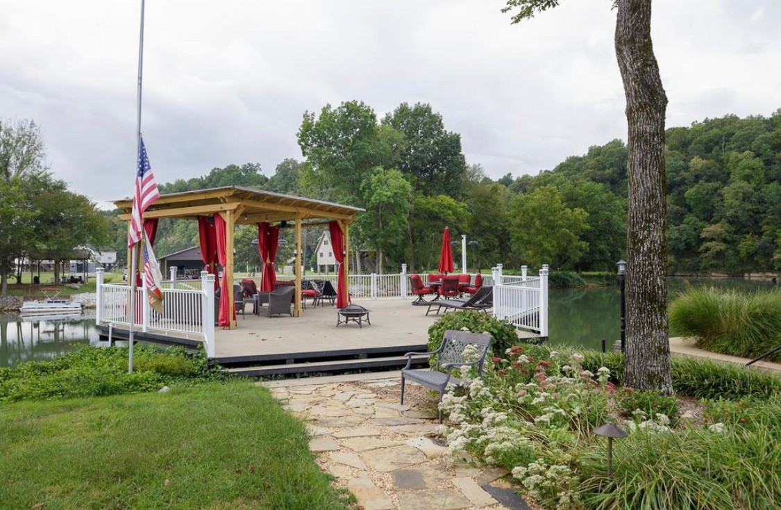 Covered lakeside dock pavilion with seating, fire pit and American flag