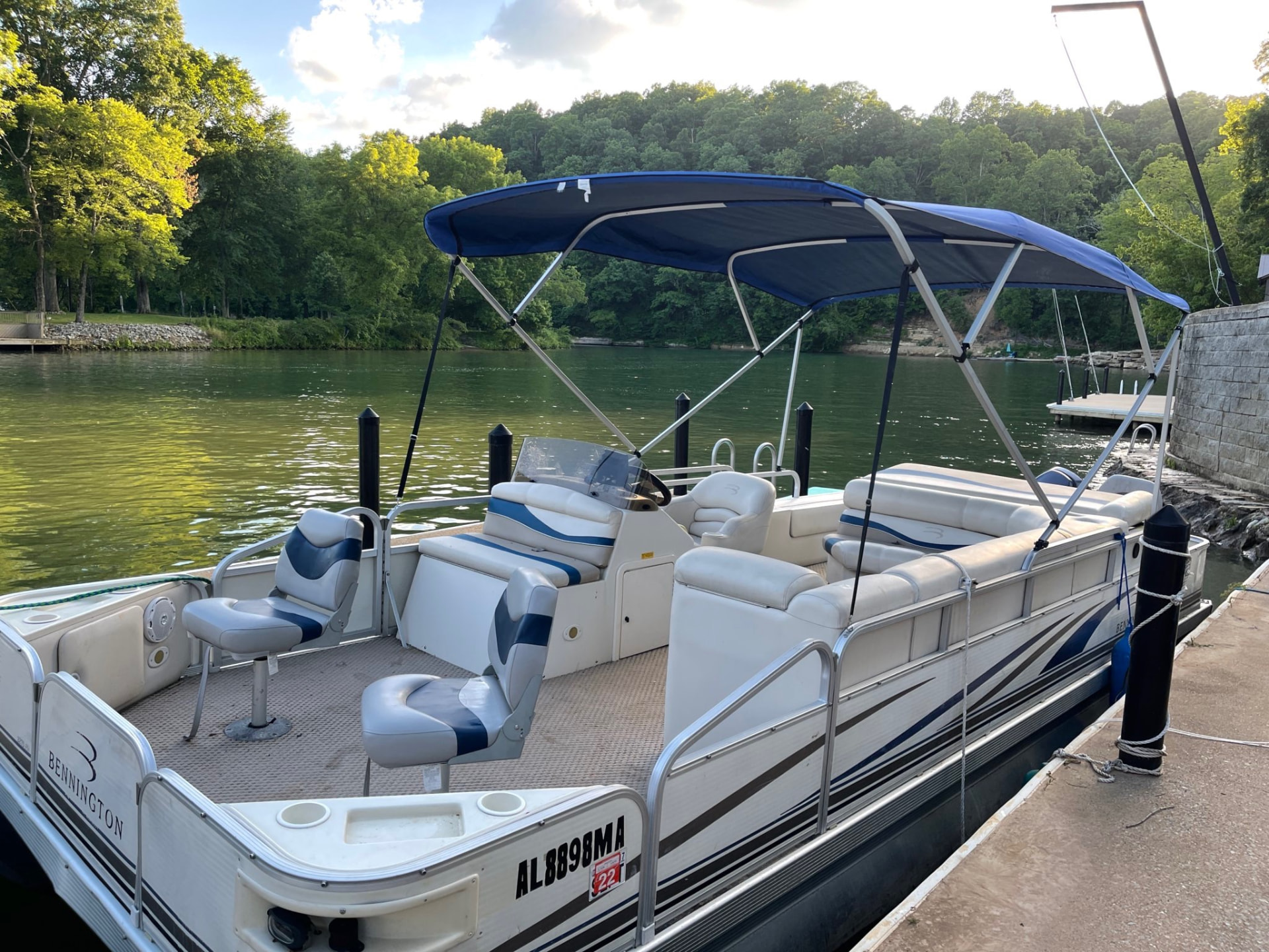 Pontoon boat with a blue canopy tied up at the dock