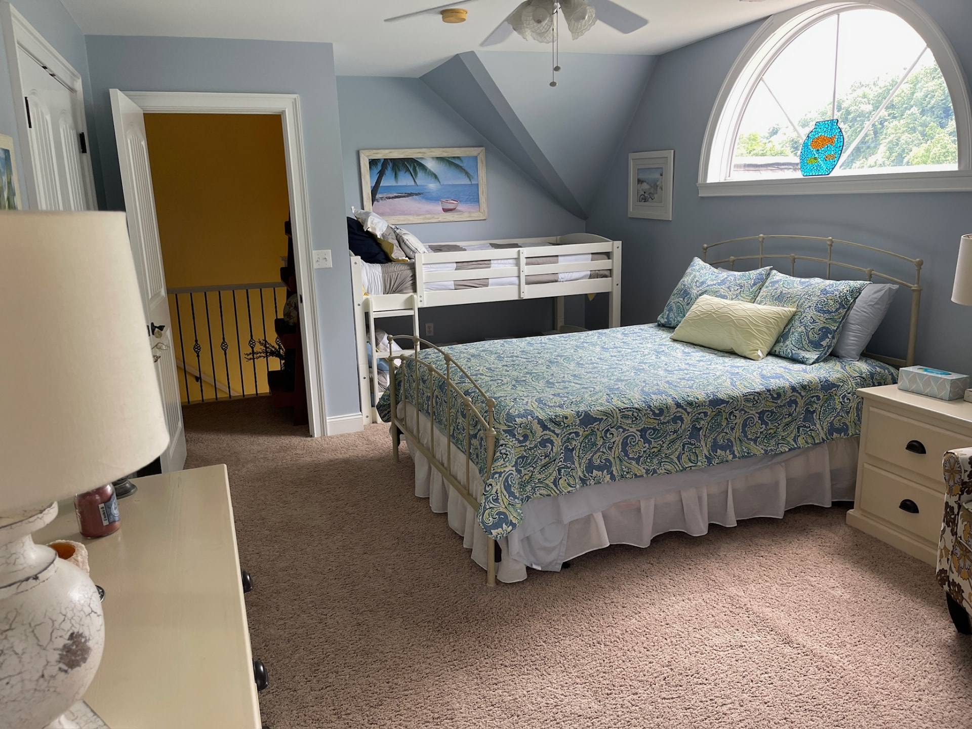 Blue bedroom with full bed, twin bunk and arched window