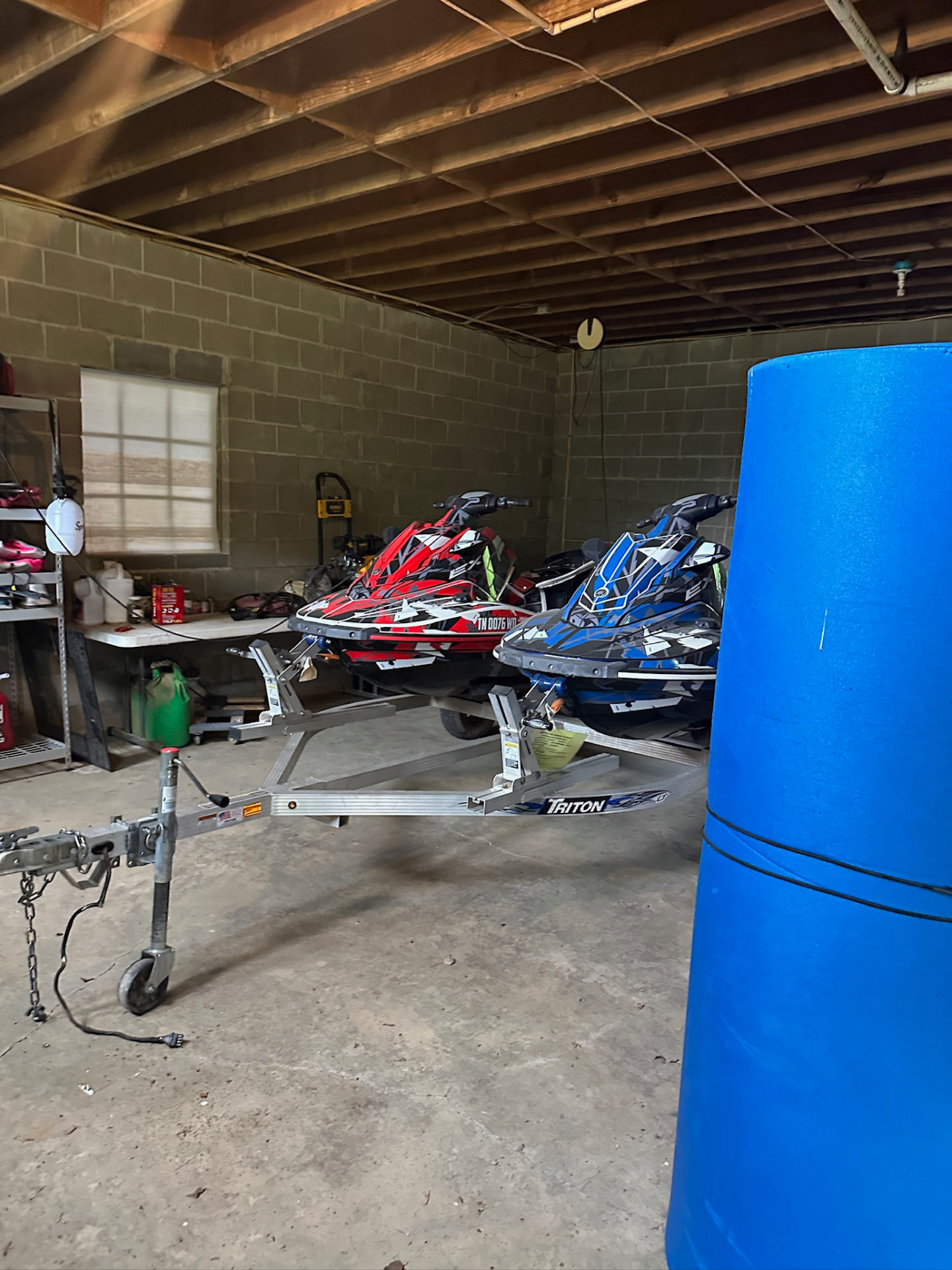 Two jet skis on a Triton trailer inside the boathouse