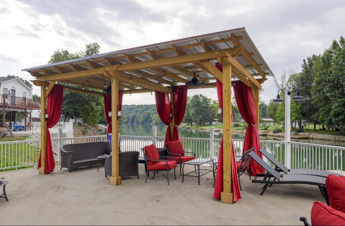 Pergola-covered deck with red curtains, lounge chairs and open water views