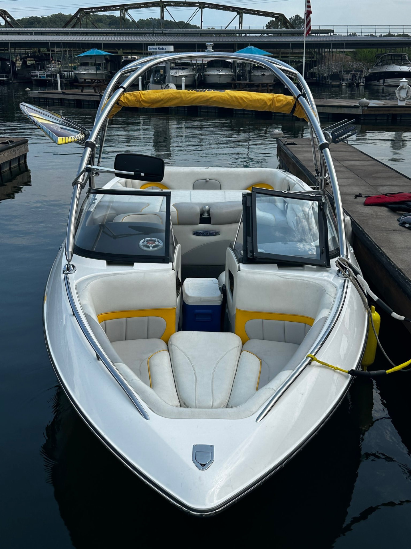 Surf boat racked with wakeboards, backed down the dock