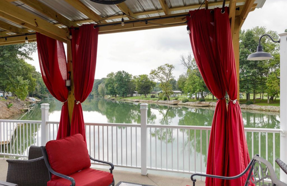 Pergola deck with red cushioned chairs overlooking the calm lake